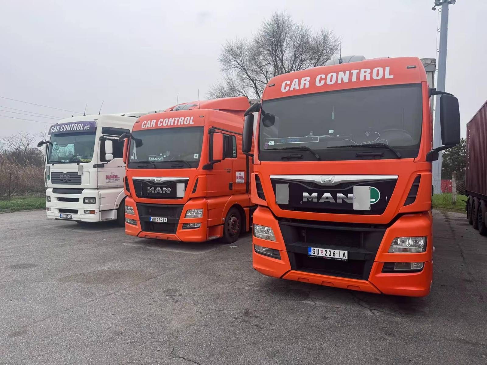 Tri MAN kamiona Car Control, jedan beli i dva narandžasta, parkirana jedan do drugog